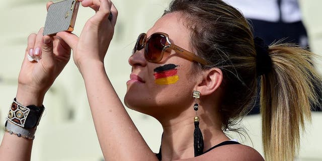 A German fan takes pictures with her phone before the start of the Group G football match between Germany and Ghana at the Castelao Stadium in Fortaleza during the 2014 FIFA World Cup on June 21, 2014. AFP PHOTO / JAVIER SORIANO