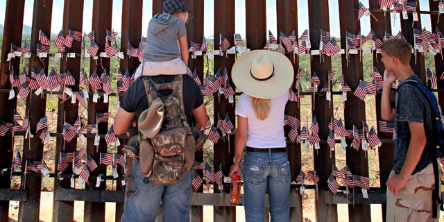 Aug. 15: From left; Steven Nanatovich, Jennifer Nanatovich, 7, Alexa Nanatovich, and Russell Nanatovich look at the flags on the Arizona-Mexico border wall in Hereford, Ariz.