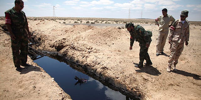 Aug. 15: A rebel fighter throws a stone into a pool of oil allegedly left by Muammar Qaddafi's troops near the town of Brega, Libya.