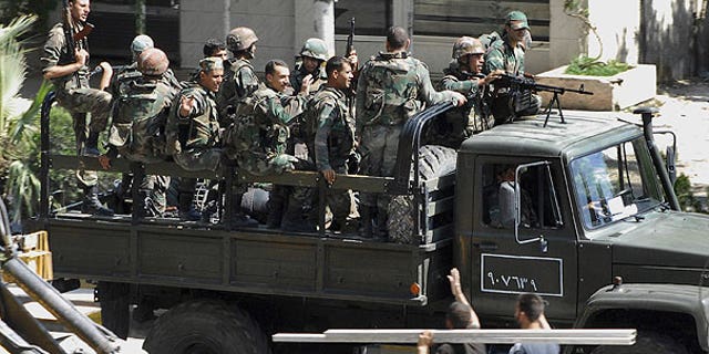 Aug. 14: In this citizen journalism image, Syrian citizens, below right, wave to Syrian troops who withdraw from the Damascus suburb of Saqba, Syria, following a campaign of raids and arrests that started overnight and continued Sunday morning.