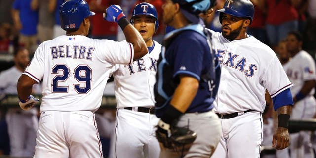 Texas Rangers third baseman Adrian Beltre (29) celebrates with teammates Shin-Soo Choo, center, and Prince Fielder after his three-run home run, while Tampa Bay Rays catcher Rene Rivera stands nearby during the sixth inning of a baseball game Saturday, Aug. 15, 2015, in Arlington, Texas. The Rangers defeated the Rays 12-4. (AP Photo/Ron Jenkins)