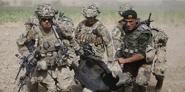July 30: An Afghan National Army soldier along with U.S soldiers carry a wounded U.S soldier following an attack to a medevac helicopter.