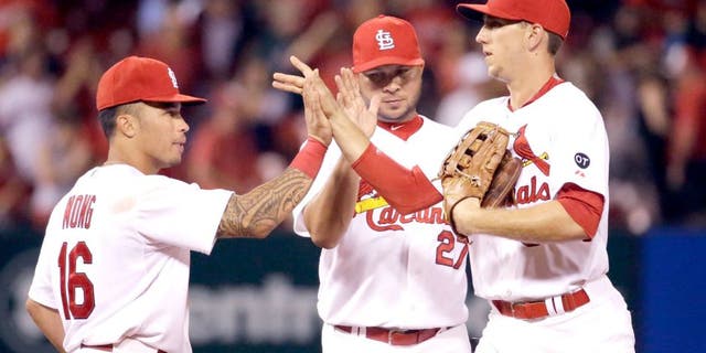 St. Louis Cardinals, from left to right, Kolten Wong, Jhonny Peralta and Stephen Piscotty celebrate following the Cardinals' 2-1 victory over the San Francisco Giants in a baseball game Monday, Aug. 17, 2015, in St. Louis. (AP Photo/Jeff Roberson)