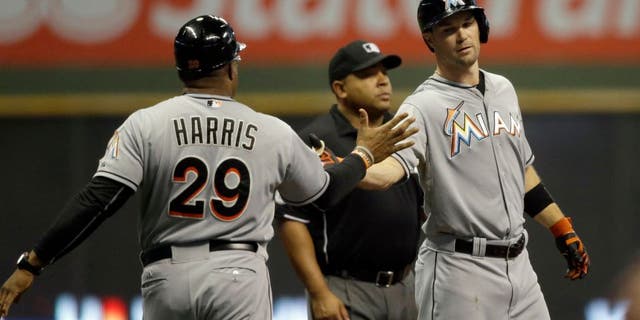 Miami Marlins' Cole Gillespie, right, is congratulated by third base coach Lenny Harris after Gillespie's three- run triple against the Milwaukee Brewers during the first inning of a baseball game, Tuesday, Aug. 18, 2015, in Milwaukee. (AP Photo/Jeffrey Phelps)