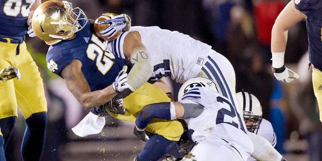 Nov 23, 2013; South Bend, IN, USA; Notre Dame Fighting Irish running back Tarean Folston (25) is tackled by BYU Cougars linebacker Uani 'Unga (41) and safety Craig Bills (20) in the third quarter at Notre Dame Stadium. Notre Dame won 23-13. Mandatory Credit: Matt Cashore-USA TODAY Sports