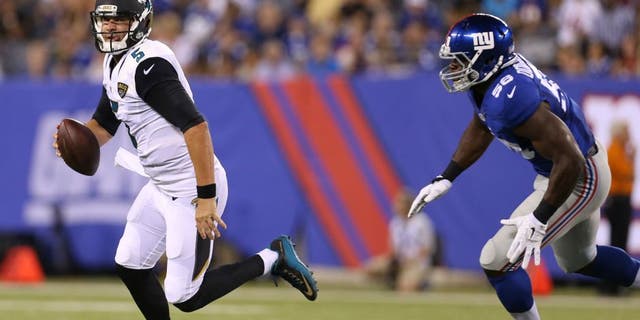 Jacksonville Jaguars quarterback Blake Bortles (5) runs away from New York Giants defensive end Owamagbe Odighizuwa (58) during the first half of a preseason NFL football game Saturday, Aug. 22, 2015, in East Rutherford, N.J. (AP Photo/Adam Hunger)
