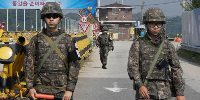 Aug. 23, 2015: A South Korean amy soldier walks as his colleague soldiers stand guard on Unification Bridge, which leads to the demilitarized zone, near the border village of Panmunjom in Paju, South Korea.