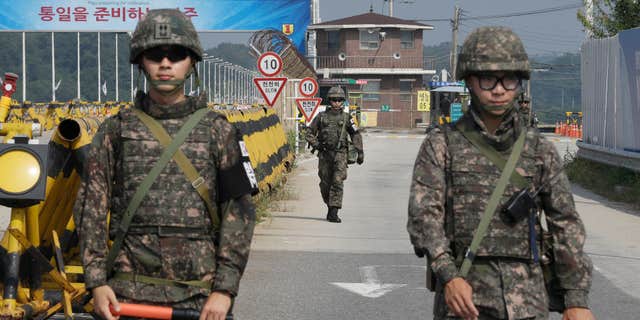 Aug. 23, 2015: A South Korean amy soldier walks as his colleague soldiers stand guard on Unification Bridge, which leads to the demilitarized zone, near the border village of Panmunjom in Paju, South Korea.