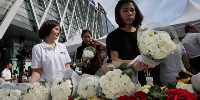 Aug. 21, 2015: People leave flowers at a shopping plaza across from the Erawan Shrine at Rajprasong intersection, the scene of Monday's bombing, for a multi-denominational religious service for victims in Bangkok, Thailand