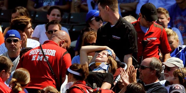 A fan is carried away after being hit a by a line-drive foul ball during the first inning of a baseball game between the Chicago Cubs and the Atlanta Braves at Wrigley Field, Sunday, Aug. 23, 2015, in Chicago. (AP Photo/Paul Beaty)
