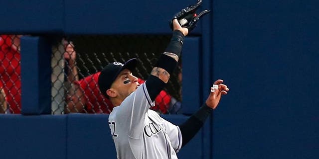 ATLANTA, GA - AUGUST 24: Right fielder Carlos Gonzalez #5 of the Colorado Rockies makes a sliding catch in the third inning during the game against the Atlanta Braves at Turner Field on August 24, 2015 in Atlanta, Georgia. (Photo by Mike Zarrilli/Getty Images)