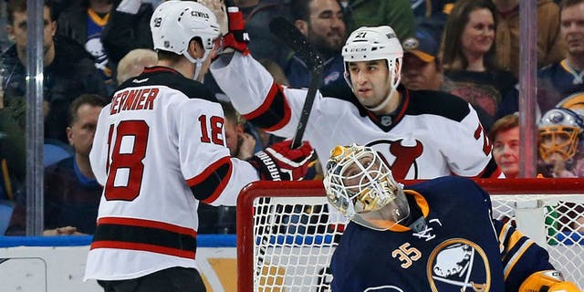 Mar 20, 2015; Buffalo, NY, USA; New Jersey Devils right wing Steve Bernier (18) celebrates with center Scott Gomez (21) after Bernier scored on Buffalo Sabres goalie Anders Lindback (35) during the second period at First Niagara Center. Mandatory Credit: Kevin Hoffman-USA TODAY Sports