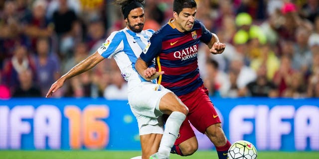 BARCELONA, SPAIN - AUGUST 29: Luis Suarez of FC Barcelona is brought down by Marcos Angeleri of Malaga CF during the La Liga match between FC Barcelona and Malaga CF at Camp Nou on August 29, 2015 in Barcelona, Spain. (Photo by Alex Caparros/Getty Images)