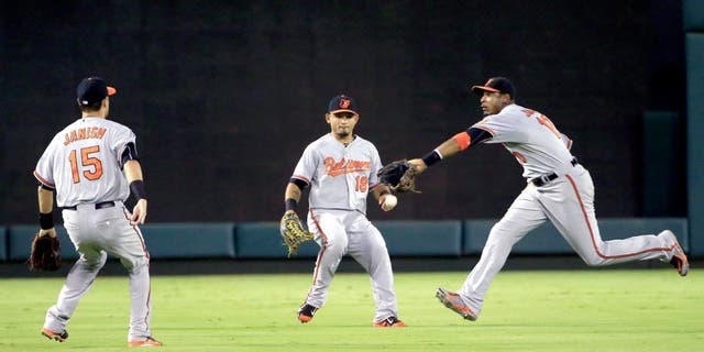 Aug 29, 2015; Arlington, TX, USA; Baltimore Orioles center fielder Adam Jones (10) and left fielder Gerardo Parra (18) and shortstop Paul Janish (15) cannot catch a fly ball during the fourth inning against the Texas Rangers at Globe Life Park in Arlington. Mandatory Credit: Kevin Jairaj-USA TODAY Sports