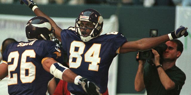 IRVING, : Minnesota Vikings receiver Randy Moss (C) celebrates his 51 yard touchdown reception on the fourth play of the game versus the Dallas Cowboys at Texas Stadium in Irving, TX, 26 November. At left is teammate Robert Smith. AFP PHOTO/PAUL BUCK (Photo credit should read PAUL BUCK/AFP/Getty Images)