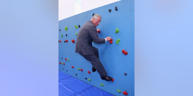 Prince Charles (Chris Jackson) climbs the traversing wall of the new gymnasium at Grainville Secondary School in St Helier, England, 18 July 2012