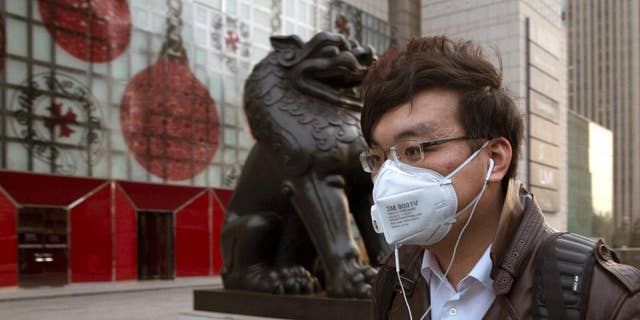 A man wears a mask on the streets of Beijing Friday, March 20, 2015. A U.S. envoy for climate change said Friday that China and the U.S. are working more closely than ever ahead of a conference this year in Paris that raises hopes for a global plan to cut greenhouse emissions. (AP Photo/Ng Han Guan)
