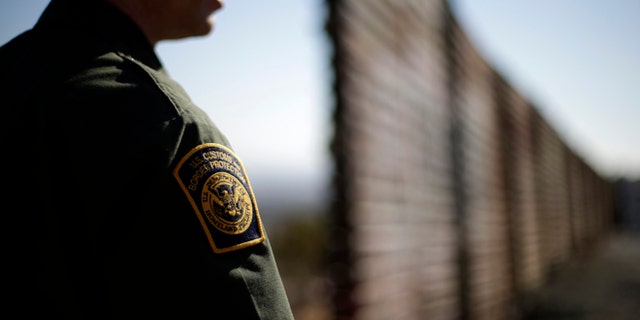 In this June 13, 2013 picture, U.S. Border Patrol agent Jerry Conlin looks to the north near where the border wall ends as is separates Tijuana, Mexico, left, and San Diego, right. Illegal immigration into the United States would decrease by only 25 percent under a far-reaching Senate immigration bill, according to an analysis by the Congressional Budget Office that also finds the measure reduces federal deficits by billions. (AP Photo/Gregory Bull)
