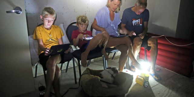 The Blinckman family use their personal devices while sheltering in a stairwell utility closet as Hurricane Irma goes over Key West, Fla., Sunday, Sept. 10, 2017. Hurricane Irma made landfall near Cudjoe Key as a Category 4 hurricane. (Charles Trainor Jr/The Miami Herald via AP)