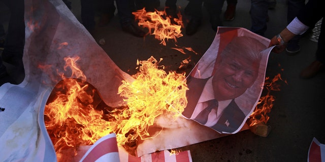 Palestinian protesters burn a poster of PresidentTrump and a representation of an American flag earlier in December.