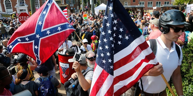 White nationalist demonstrators walk into a park surrounded by counter-protesters.