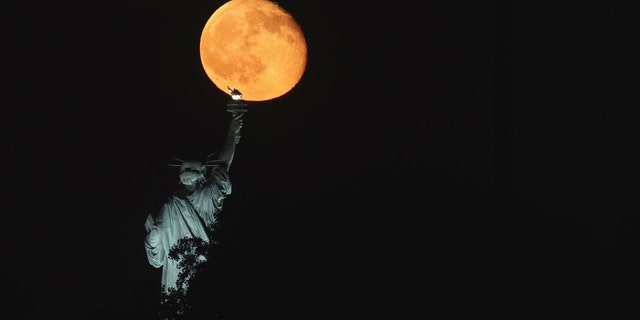 JERSEY CITY, NJ - JUNE 11: The moon rises behind the Statue of Liberty in New York City on June 11, 2017 as seen from Jersey City, NJ. (Photo by Gary Hershorn)