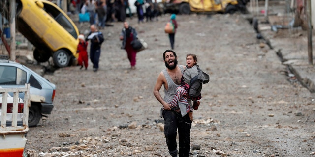 A man cries as he carries his daughter from an ISIS-controlled area of Mosul, Iraq