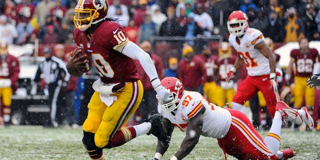 Dec 8, 2013; Landover, MD, USA; Washington Redskins quarterback Robert Griffin III (10) avoids the tackle by Kansas City Chiefs defensive end Allen Bailey (97) during the second quarter at FedEx Field. Mandatory Credit: Brad Mills-USA TODAY Sports