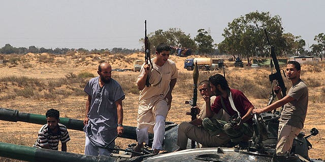 September 1: Freedom fighters climb on a tank for a lookout at a defensive outpost, some 30 kilometers outside Misrata, Libya.