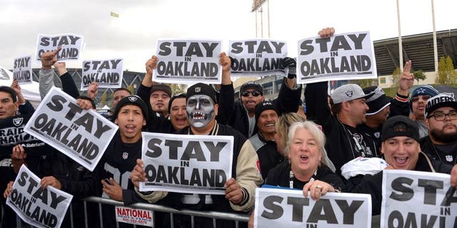Nov 20, 2014; Oakland, CA, USA; Oakland Raiders fans tailgate while holding signs the read "Stay in Oakland" before the NFL football game against the Kansas City Chiefs at O.co Coliseum. Mandatory Credit: Kirby Lee-USA TODAY Sports