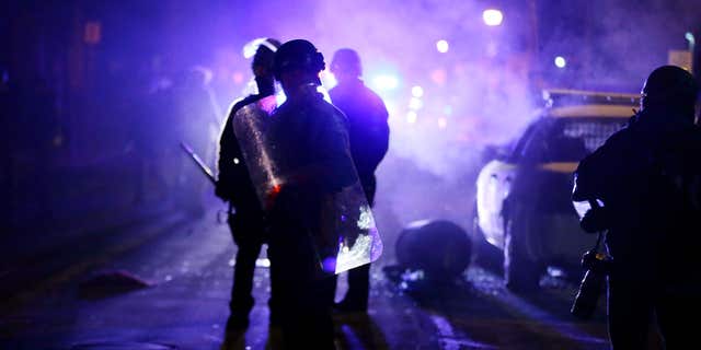 Nov. 25, 2014: Police officers watch protesters as smoke fills the streets in Ferguson, Mo. after a grand jury's decision in the fatal shooting of Michael Brown.