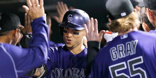 Colorado Rockies' Carlos Gonzalez, center, is congratulated by teammates as he returns to the dugout after hitting a two-run home run off San Francisco Giants relief pitcher George Kontos in the fourth inning of a baseball game, Thursday, Sept.. 3, 2015, in Denver. (AP Photo/David Zalubowski)