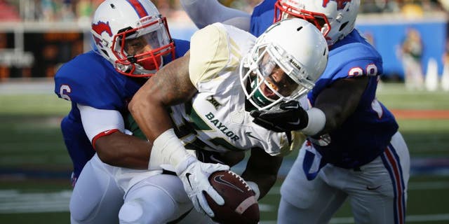 Baylor running back Shock Linwood (32) runs against SMU defenders Shakiel Randolph, right, and Jesse Montgomery (6) during the first half of an NCAA college football game Friday, Sept. 4, 2015, in Dallas. (AP Photo/LM Otero)