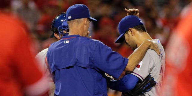 Texas Rangers pitching coach Mike Maddux, center, confers with starting pitcher Martin Perez, center right, and catcher Bobby Wilson after Perez walked Los Angeles Angels' Albert Pujols, foreground right, during the third inning of a baseball game, Friday, Sept. 4, 2015, in Anaheim, Calif. (AP Photo/Jae C. Hong)