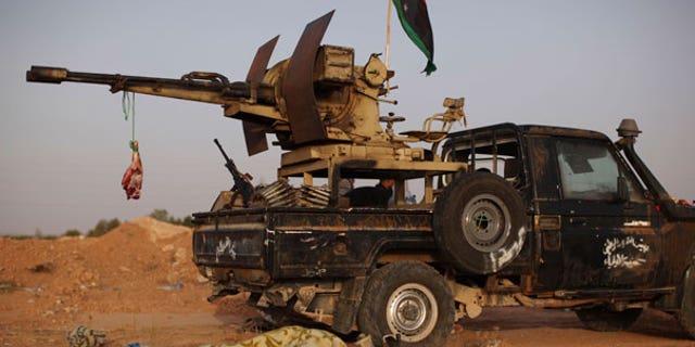 Sept. 5: A rebel fighter sleeps next to a goat's carcass hanging from an anti-aircraft gun at a checkpoint between Tarhouna and Bani Walid in Libya.