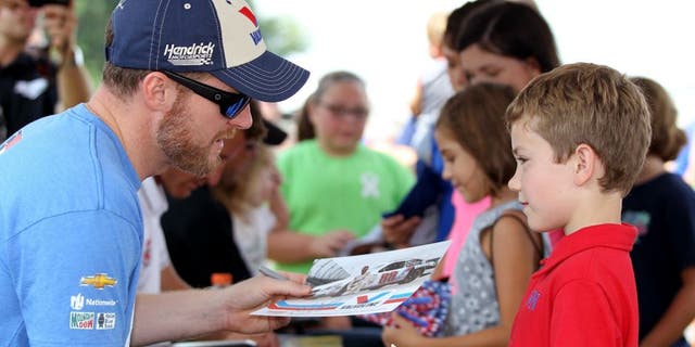 DARLINGTON, SC - SEPTEMBER 05: Dale Earnhardt Jr., driver of the #88 Valvoline Chevrolet, left, signs his autograph for young fans at an autgraph session prior to qualifying for the NASCAR Sprint Cup Series Bojangles' Southern 500 at Darlington Raceway on September 5, 2015 in Darlington, South Carolina. (Photo by Kena Krutsinger/Getty Images)