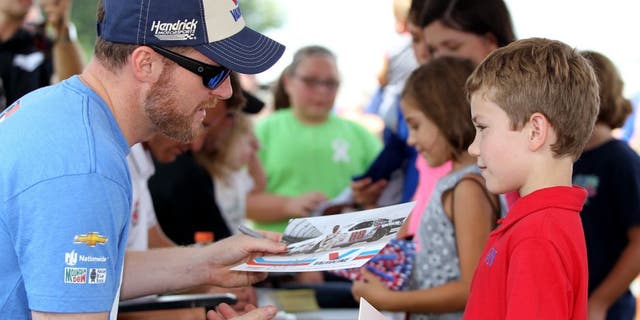 DARLINGTON, SC - SEPTEMBER 05: Dale Earnhardt Jr., driver of the #88 Valvoline Chevrolet, left, signs his autograph for young fans at an autgraph session prior to qualifying for the NASCAR Sprint Cup Series Bojangles' Southern 500 at Darlington Raceway on September 5, 2015 in Darlington, South Carolina. (Photo by Kena Krutsinger/Getty Images)