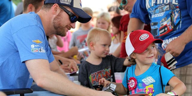 DARLINGTON, SC - SEPTEMBER 05: Dale Earnhardt Jr., driver of the #88 Valvoline Chevrolet, left, signs his autograph for young fans at an autgraph session prior to qualifying for the NASCAR Sprint Cup Series Bojangles' Southern 500 at Darlington Raceway on September 5, 2015 in Darlington, South Carolina. (Photo by Kena Krutsinger/Getty Images)