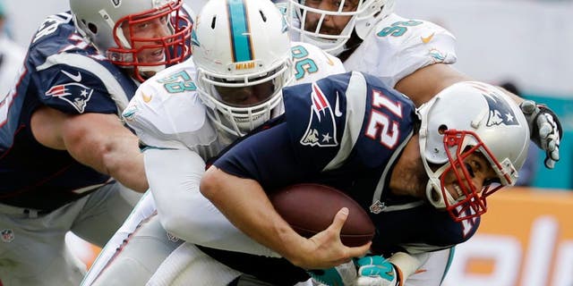 New England Patriots quarterback Tom Brady (12) is sacked by Miami Dolphins linebacker Chris McCain (58), during the second half of an NFL football game, in Miami Gardens, Fla., Sunday Sept. 7, 2014. (AP Photo/Lynne Sladky)