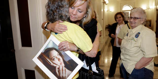 Sept. 9, 2015: Debbie Ziegler holds a photo of her daughter, Brittany Maynard, as she receives congratulations from Ellen Pontac, after a right-to die measure was approved by the Assembly in Sacramento, Calif.