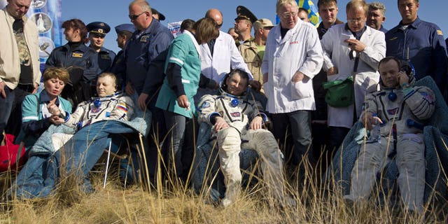 In this image provided by NASA Expedition 28 Commander Andrei Borisenko, left, Flight Engineers Alexander Samokutyayev, center, and Ron Garan, sit in chairs outside the Soyuz Capsule just minutes after they landed in a remote area outside the town of Zhezkazgan, Kazakhstan.