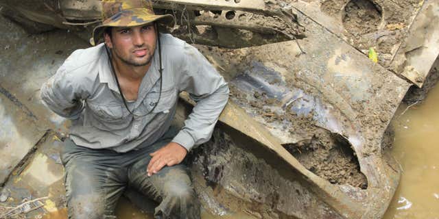 In this 2014 photo provided by Pacific Wrecks, Justin Taylan, founder and director of Pacific Wrecks poses at a World War II airplane wreck site in Papua New Guinea (PNG).