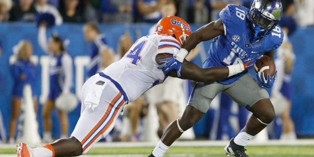 Sep 19, 2015; Lexington, KY, USA; Kentucky Wildcats running back Stanley Boom Williams (18) runs the ball against Florida Gators defensive lineman Bryan Cox (94) during the game at Commonwealth Stadium. Florida defeated Kentucky 14-9. Mandatory Credit: Mark Zerof-USA TODAY Sports