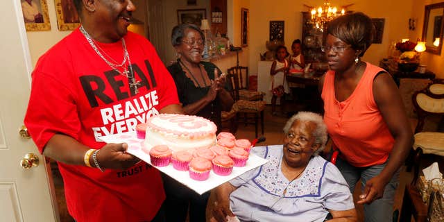 FILE- In this July 25, 2015, file photo, Terrance Jackson, left, Doris Ware, second from left, and Beverly Booker, right, sing "Happy Birthday To You" to Bernice Williams, seated, as she celebrates her 103rd birthday in the Mill City neighborhood of Dallas.