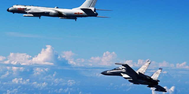 In this Sunday, Sept. 25, 2016, photo released by Xinhua News Agency, Chinese People's Liberation Army Air Force Su-30 fighter, right, flies along with a H-6K bomber as they take part in a drill near the East China Sea.