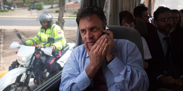 Brazilian Senator Aecio Neves speaks on his cell phone as he rides in a van with other Brazilian senators, escorted by Bolivarian Police on motorcycles, after departing the airport in La Guaira, Venezuela, Thursday, June 18, 2015. The group of Brazilian senators failed to reach the capital city of Caracas twice, due to traffic caused by a demonstration and road maintenance. The delegation had traveled to Venezuela to meet with members of Venezuela's opposition but returned to the airport to fly back to Brazil. (AP Photo/Ariana Cubillos)