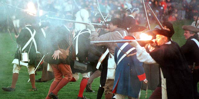 FILE - In this April 15, 2000, file photo, Revolutionary War re-enactors portraying colonial militiamen fire on British regular soldiers in the Battle of Lexington on the Lexington Green in Lexington, Mass.