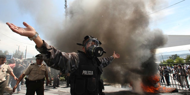 Sept. 30: A police officer demonstrates next to a bonfire during a protest of police officers and soldiers against a new law that cuts their benefits at a police base in Quito, Ecuador.