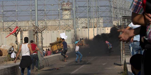 FILE - In this Oct. 16, 2015 file photo, Palestinian demonstrators hurl stones at Israeli soldiers during clashes at the entrance of Erez border crossing between the Gaza Strip and Israel, in the northern Gaza Strip. An Israeli advocacy group is reporting a sharp jump in the number of Palestinians from the Gaza Strip who have been summoned for questioning by Israeli security agents as a condition for leaving the blockaded territory. Gisha, which pushes for freedom of movement for Gaza’s 1.8 million people, says more than 1,200 Gazans underwent interrogations during the first half of this year. (AP Photo/Adel Hana, File)