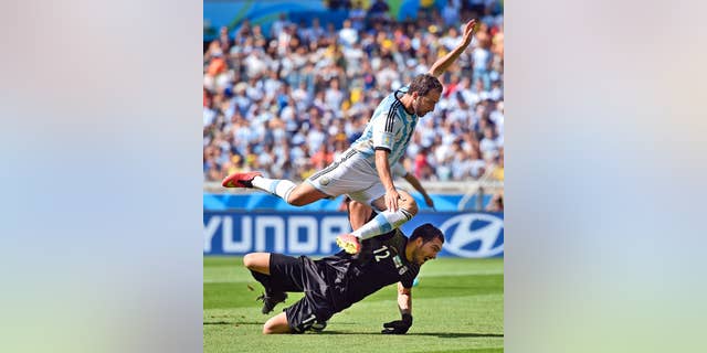 Argentina's Gonzalo Higuain leaps over Iran's goalkeeper Alireza Haghighi after taking a shot on goal during the group F World Cup soccer match between Argentina and Iran at the Mineirao Stadium in Belo Horizonte, Brazil, Saturday, June 21, 2014. (AP Photo/Martin Meissner)
